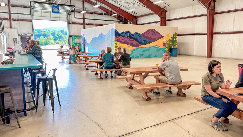 Visitors mingle around drinks and food at Longmire Springs Brewing in Packwood on Thursday, Aug. 10, 2023.