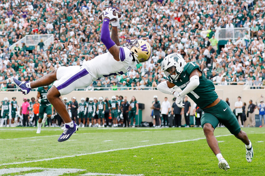 Washington Huskies wide receiver Ja'Lynn Polk goes high for a long catch before Michigan State Spartans defensive back Jaden Mangham can close during the first quarter Saturday, Sept. 16, 2023 in East Lansing, MI.