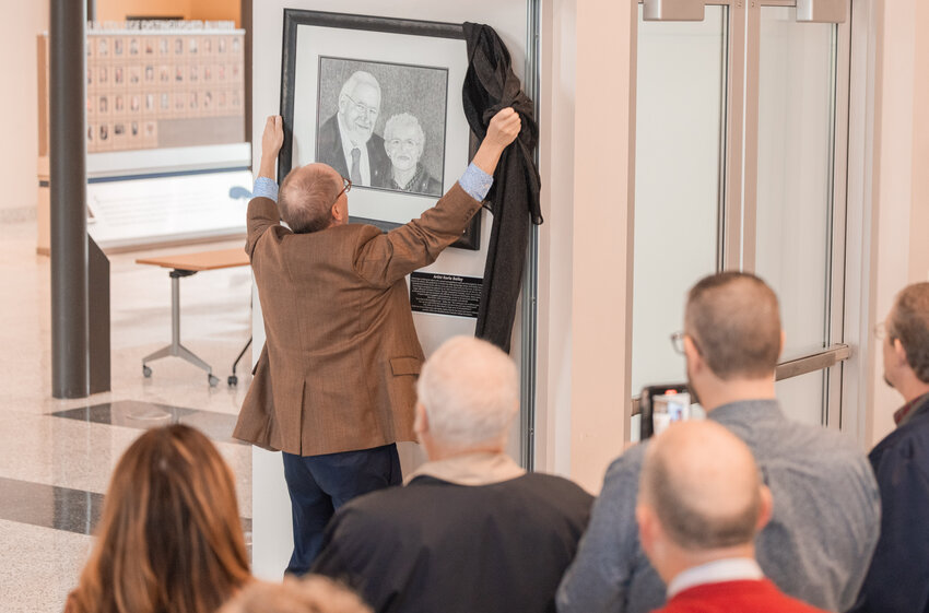 Bob Mohrbacher, president of Centralia College, unveils a portrait of Leon and Rose Bowman at the entrance to the Bowman Rotary Banquet Room inside the TransAlta Commons during a ceremony to honor their lives and work on Monday, Oct. 16. Their niece Karla Bailey completed the portrait and donated it to Centralia College in their honor.