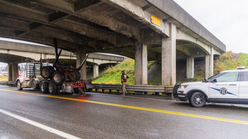 The driver of a semi-truck looks up to an underpass for Interstate 5 along West Forest Napavine Road on Wednesday, Dec. 6, after the truck struck the cement support structures under the bridge and became stuck between supports.