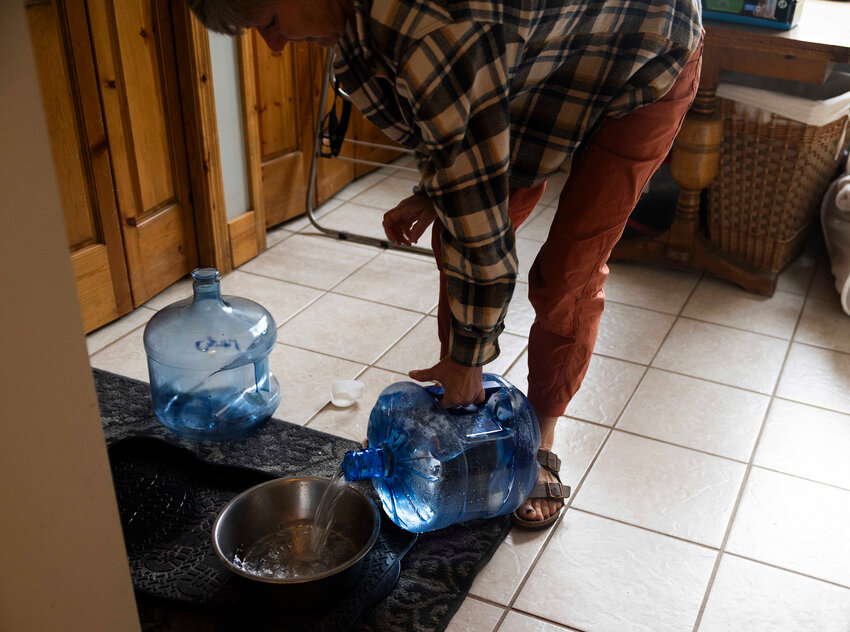 Using the water provided by the Air Force, Marcie Zambryski fills bowls up for her two boxers Livie and Louie. Her home is near Deep Creek, eight miles away from the Fairchild Air Force Base. Photographed on Aug. 30, 2023.