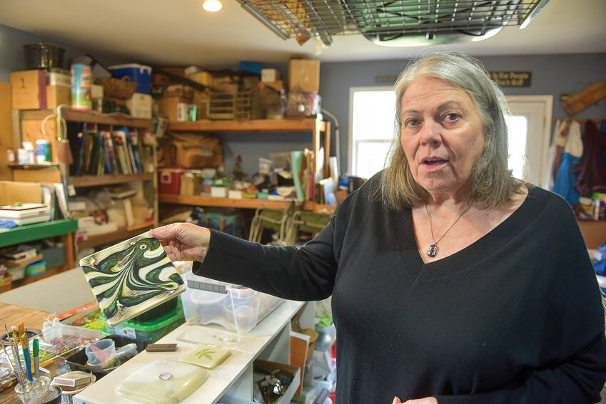 Jan Downs explains a glass artwork she created using a mixture of molten glasses swirled with an iron rod for a swooping pattern.