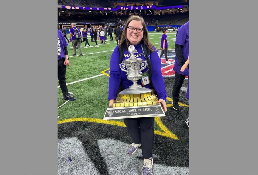 University of Washington's assistant director of communications, Hailee Roe, poses with the Sugar Bowl trophy on Jan. 1 after the Huskies defeated the Texas Longhorns 37-31.
