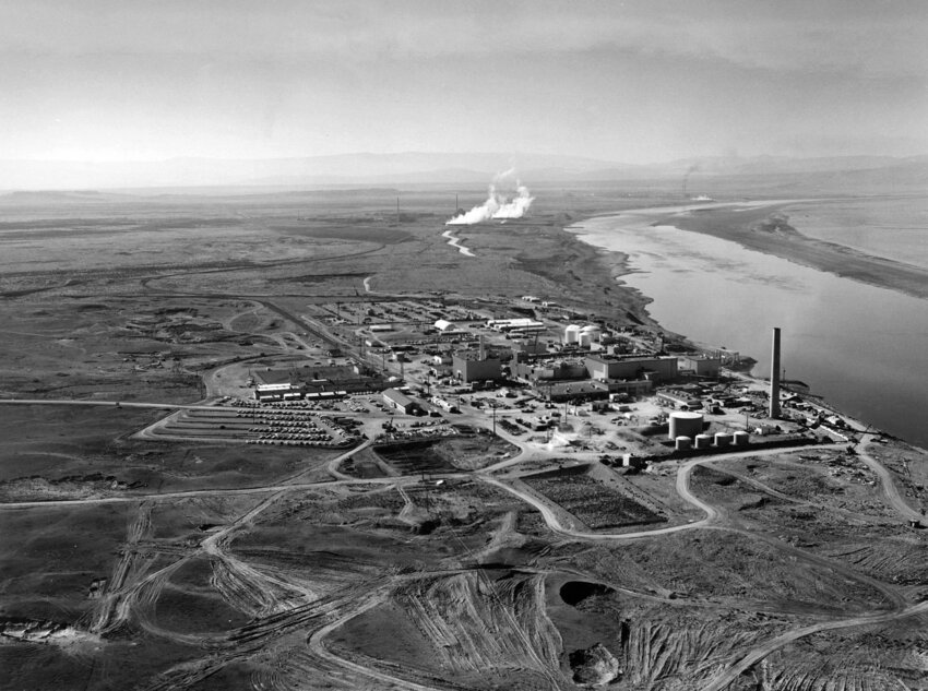 Nuclear reactors line the riverbank at the Hanford Site along the Columbia River in January 1960. The N Reactor is in the foreground, with the twin KE and KW Reactors in the immediate background. The historic B Reactor, the world's first plutonium production reactor, is visible in the distance.