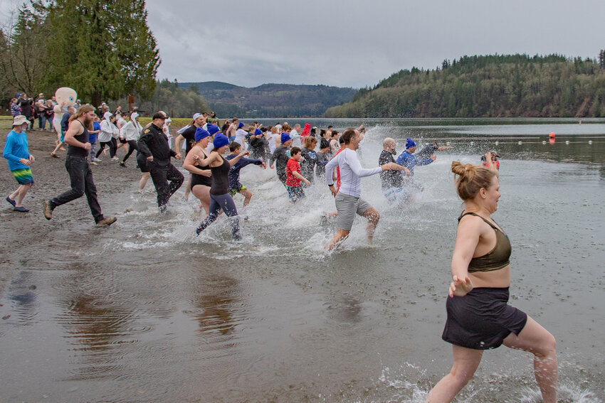 Participants in the 2024 Lewis County Polar Plunge kick up water running into Mayfield Lake on Saturday, Jan. 27.