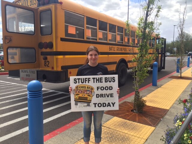 A volunteer stands with a sign at the annual &ldquo;Stuff the Bus&rdquo; food drive, which collects items and cash donations for the North County Community Food Bank.