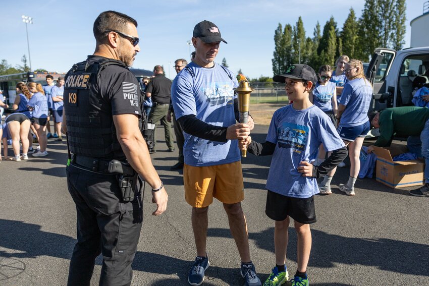 Rep. Peter Abbarno hands his son, Antonio Abbarno, the torch during the Lewis County Special Olympics Law Enforcement Torch Run on Friday, May 31, 2024.