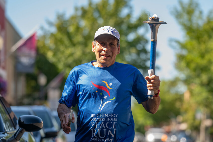 Arpan DeAngelo, age 72, makes his way down North Tower Avenue holding the &ldquo;Peace Torch&rdquo; as the nationwide Sri Chinmoy Oneness-Home Peace Run passes through Centralia on Thursday, June 20.