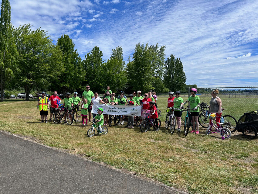 Local riders pose for a photo with a sign commemerating the Ride The Willapa Event.
