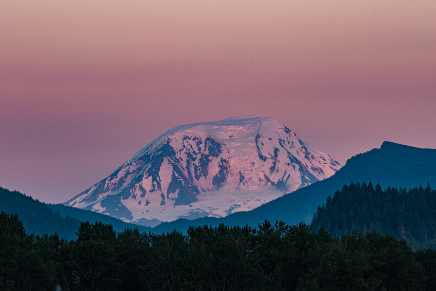 Mount Adams glows pink in the alpenglow at sunset on Saturday, July 6, as seen from Peters Road in Randle.