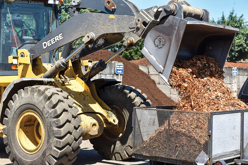 A worker at City Bark &amp; Recycling loads a yard of wood chips into a customer&rsquo;s truck. Landscaping materials such as gravel and soil are recycled from waste and repurposed for landscaping projects.