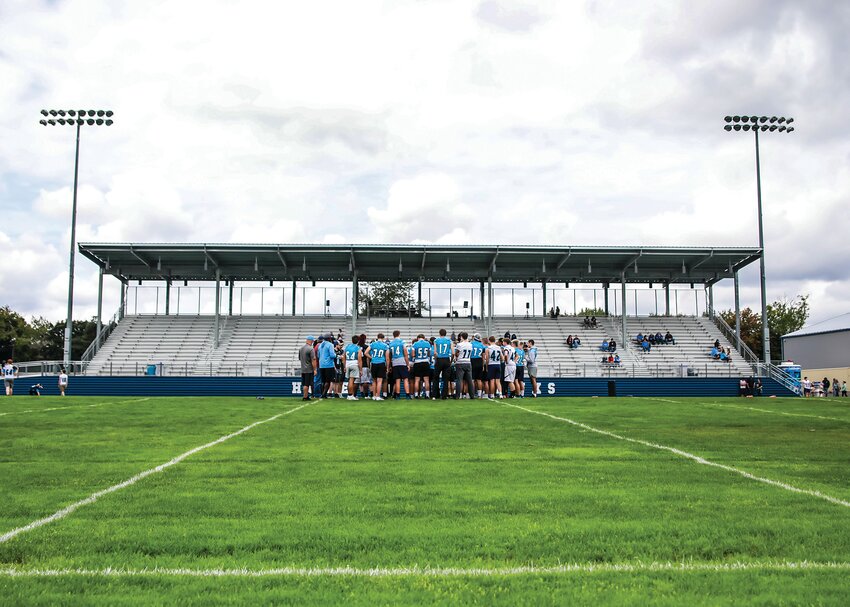 Hockinson Hawks players, coaches and alumni huddle up at midfield prior to their two-hand touch, seven-on-seven football game during football season kickoff event and fundraiser on Saturday, Aug. 24.