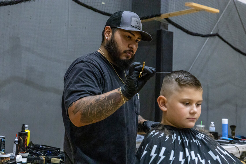 Alberto Isguerra, of Toro&rsquo;s Barbershop, shaves Hunter Lowther&rsquo;s hair during a back-to-school event at NW Sports Hub in Centralia on Saturday, Aug. 24. This is Isguerra&rsquo;s second year hosting the event to provide kids in the community with free school supplies and fresh haircuts before school starts.