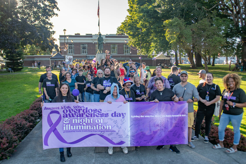 Roughly 50 people pose for a photo at the start of a remembrance walk during an overdose awareness event held at George Washington Park in Centralia on Thursday, Aug. 29.