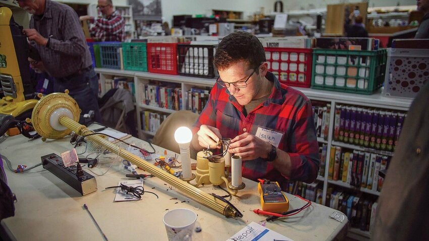 A Repair Clark County volunteer rewires a lamp during a community event hosted by Columbia Springs in Vancouver. The program offers free repairs for household items and teaches participants how to maintain them.