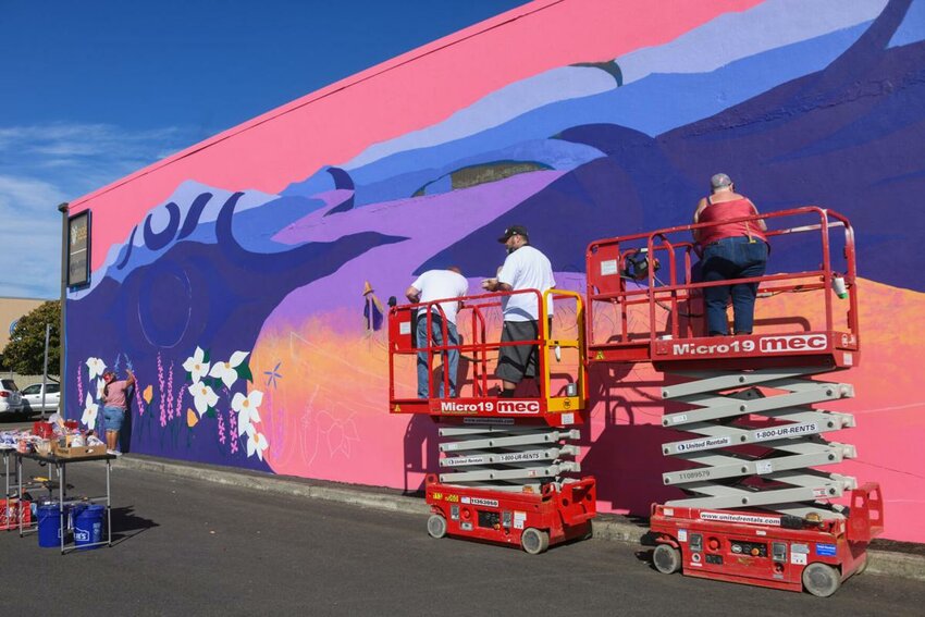 Cowlitz Tribal member and artist Sarah Folden, right, and volunteers paint a mural on the side of the Pals For Hair building on Saturday, Sept. 28 in Longview.