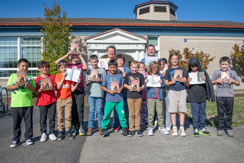 New York Times bestselling author John Schu, back right, poses for a photo with teacher Dennis Lorton, back left, and his fourth grade class outside of Edison Elementary School in Centralia on Thursday, Oct. 10.