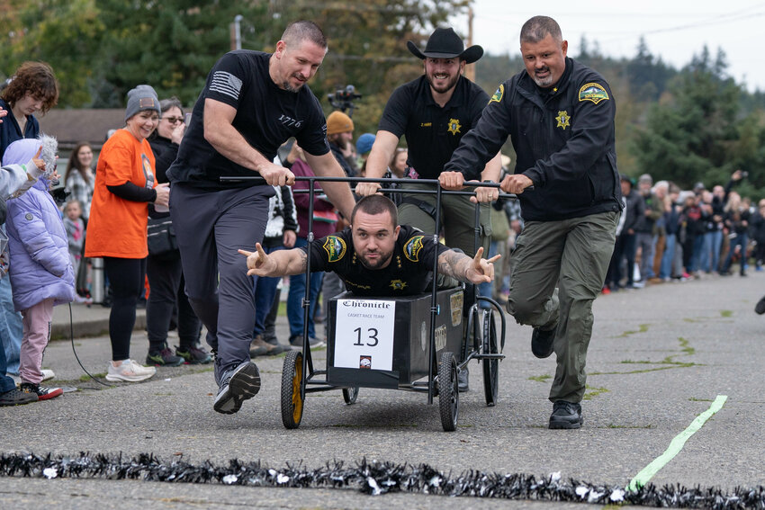 Thurston County Sheriff Derek Sanders celebrates as his team pushes their casket across the finish line during the annual Boo-coda casket races in Bucoda on Saturday, Oct. 19.