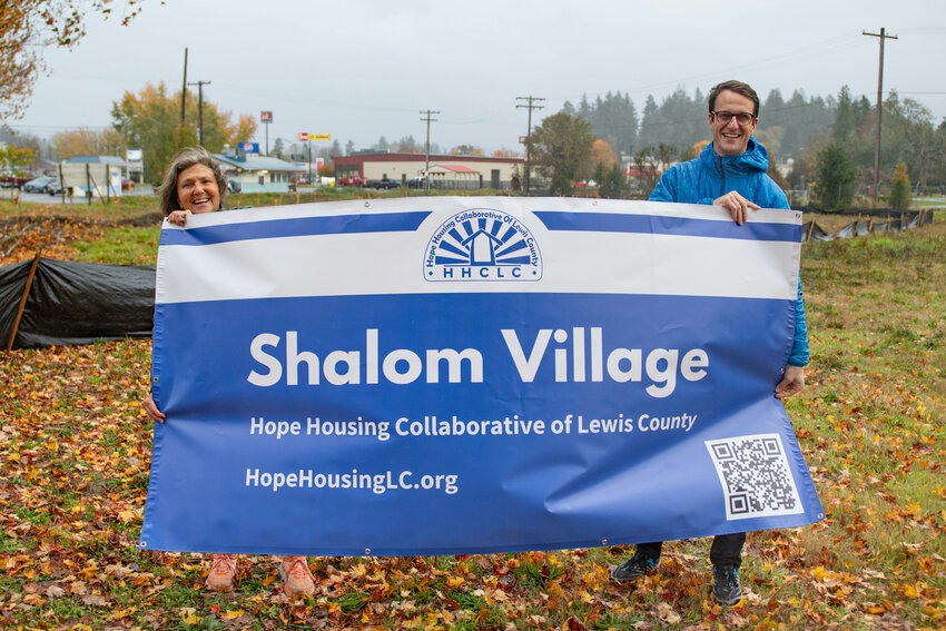 Jennifer Polley, left, and Mark McHugh, of the Hope Housing Collaborative of Lewis County, smile for a photo with a sign at the future site of the Shalom Village project outside of Harrison Square Presbyterian Church  in Centralia on Monday, Nov. 4.