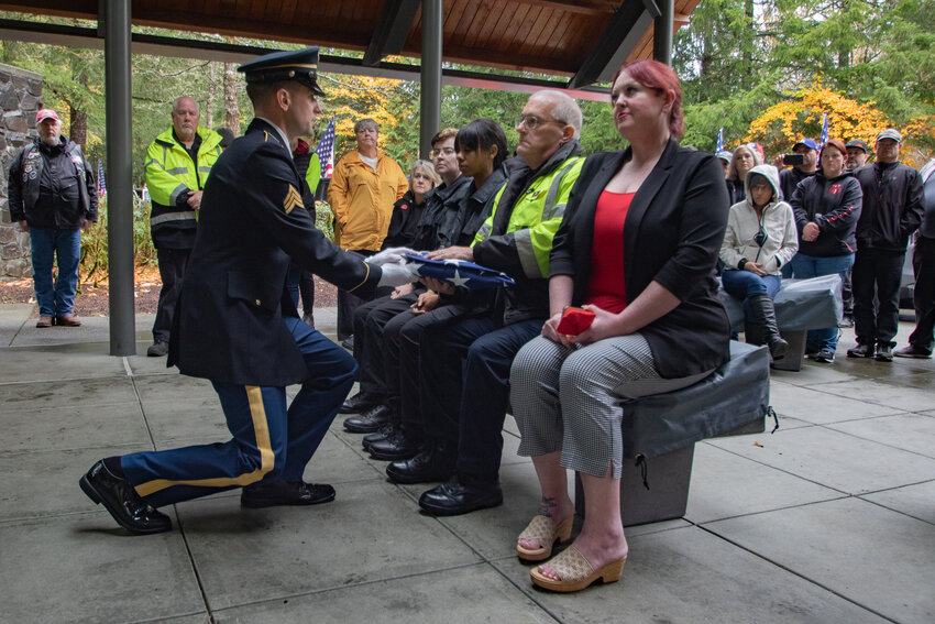 A U.S. Army honor guard member presents Lewis County Coroner Warren McLeod with the ceremonial burial flag for Army veteran Lawrence S. Givens on Friday, Nov. 1, at Tahoma National Cemetery after his remains were left unclaimed in the county for nearly a year.