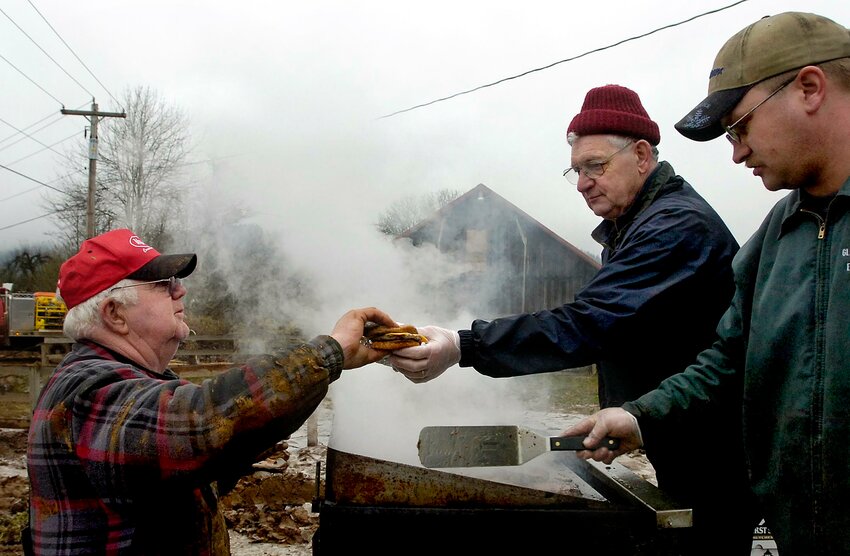 Lee Coumbs and Brandon Best serve up hamburgers at the Pete Dykstra dairy in Curtis on Dec. 20, 2007, during cleanup work after the Chehalis River flood. Coumbs died earlier this month at age 82.