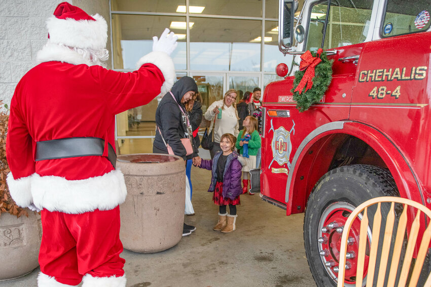 Santa waves to children waiting in line during a meet-and-greet event held in memory of Daryl Lund at his former business Minuteman Press in Chehalis on Sunday, Dec. 22.