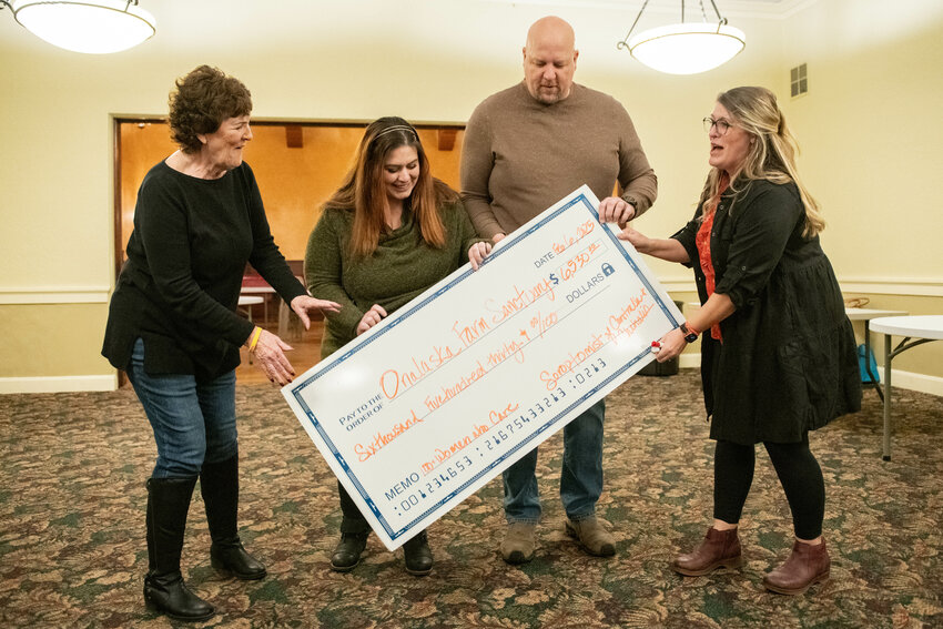 Jessica Kinney, far right, presents a check to Jessica and Kyle York of Onalaska Farm Sanctuary, middle, after their organization was named the recipient of the evening&rsquo;s donation during a 100+ Women Who Care event at the Lewis and Clark Hotel in Centralia Thursday, Feb. 6. Event organizer Vanessa Horning is at left.