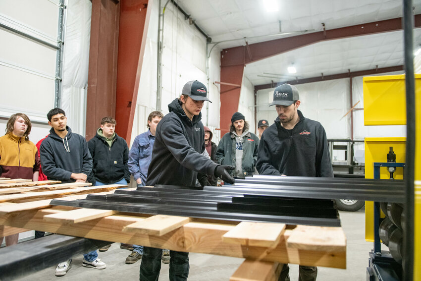 Macaw Metals employees Hunter Murphy, right, and Seth Meister operate a machine while demonstrating how sheets of metal roofing are formed during the W.F. West High School construction and woodworking class visit to Macaw Metals in Chehalis on Tuesday, Feb. 11.