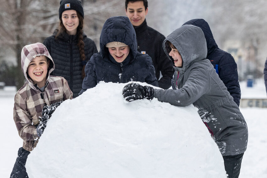 Kids attempt to roll a giant snowball home on the Centralia College campus on Thursday, Feb. 13.
