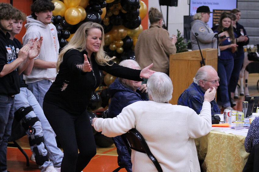 Auctioneer Cindy Schorno (left) offers to hug a community member that purchased an item during Rainier Education Foundation's auction on March 23, 2024.