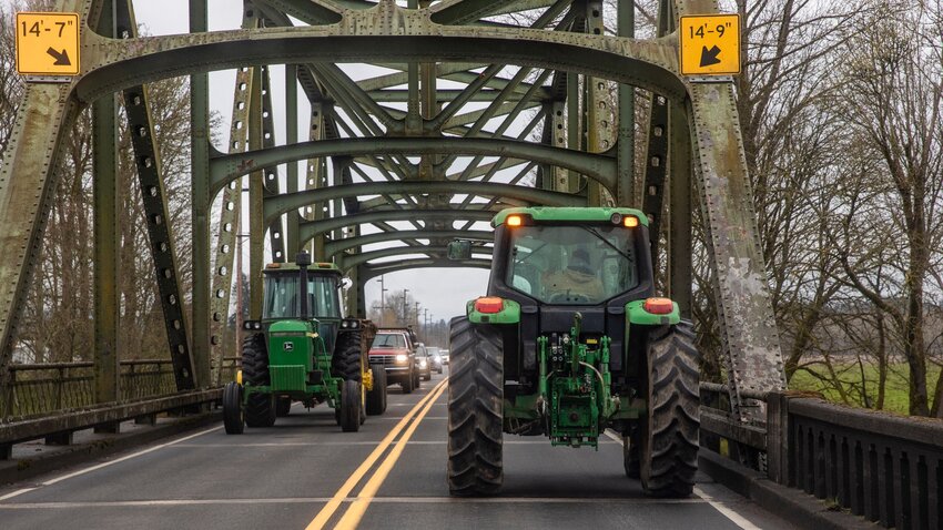 Tractor drivers gesture toward one another while traveling in opposite directions over the Chehalis River bridge along state Route 6