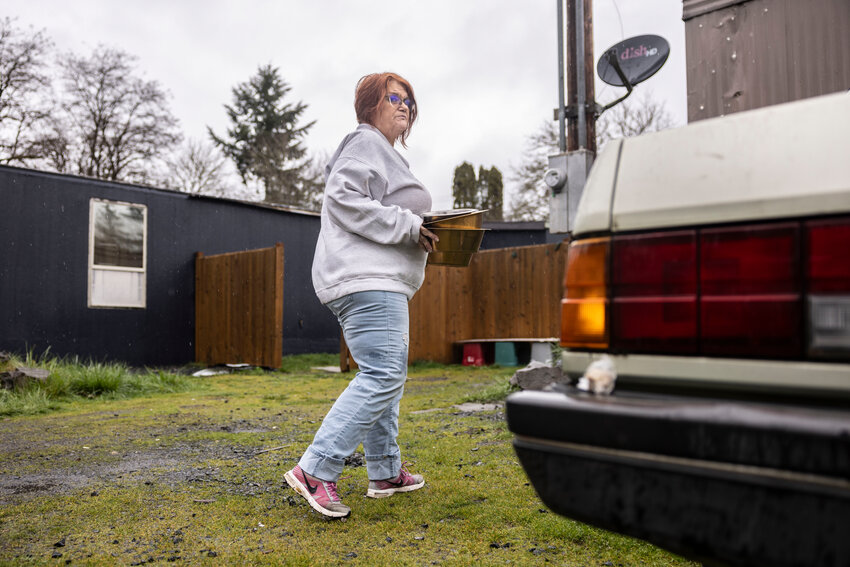Patti Angeliz Amos, of Valhalla Canine Rescue, walks with bowls of cat food to feed cats Thursday, March 20 , at the residence where Don Piccolo and Kim Torres were found murdered in Winlock.