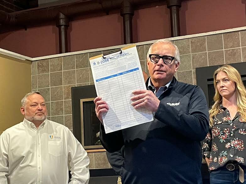 Greg Lane, executive vice president of the Building Industry Association of Washington, holds a petition for Initiative 2066, the ballot measure aimed at blocking local and state efforts to transition away from use of natural gas. Anthony Anton, president of the Washington Hospitality Association, and Ryann Blake, owner of Chimney Techniques in Aberdeen, joined a news conference May 15, 2024 in Olympia, Wash. to kick off signature gathering. (Jerry Cornfield/Washington State Standard)