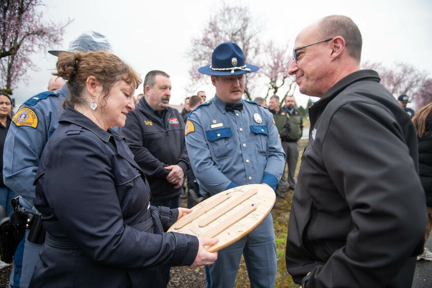 The parents of fallen State Trooper Justin Schaffer, Sheila and Glenn Schaffer, smile while reading the signatures of their son's former unit members on the back of an honorary plaque during a ceremony at the Washington State Patrol Chehalis Detachment Office honoring Trooper Justin R. Schaffer on the five-year anniversary of his death, Monday, March 24, 2025.