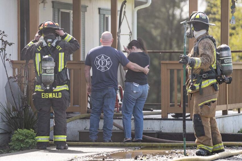 A resident is consoled while viewing the damage of a structure fire after it was extinguished west of Chehalis on Tuesday, April 8.