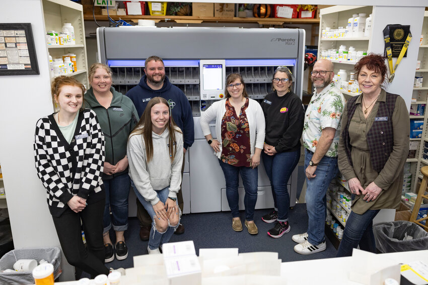 From the left, Hailee Quinby, Crystal Cooper, Maleah Wink, Dustin Overby, Courtney Quinby, Carrie Bauer, Jeff Hawkins and Gayle Roberts pose for a photo at the Centralia Pharmacy with the new vial-filling robot, the Parata Max 2, on Thursday, April 17.