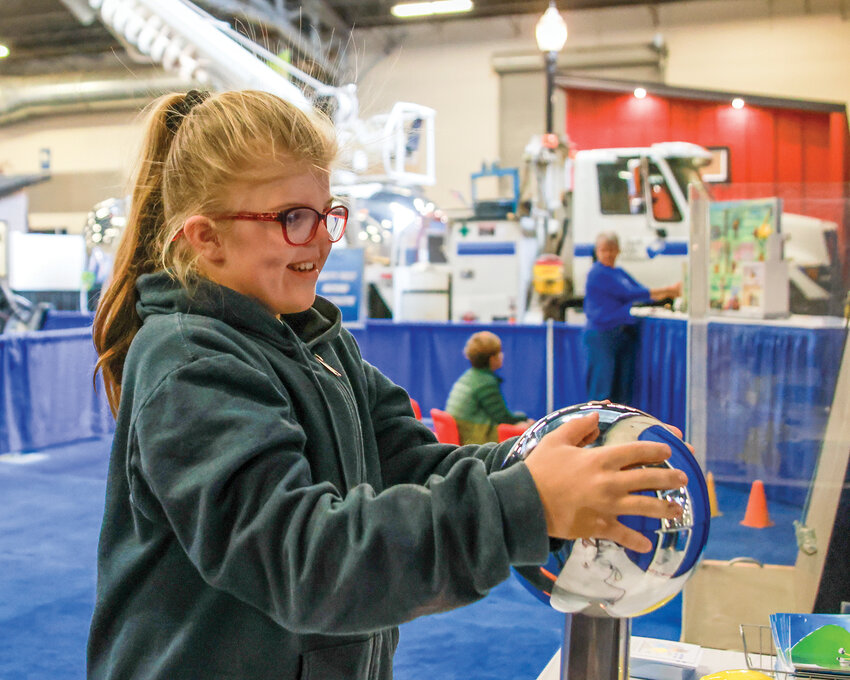 Sonja Lee's hair stands up while holding onto the Van de Graaff generator at the Home and Garden Idea Fair at the Clark County Event Center in 2024.