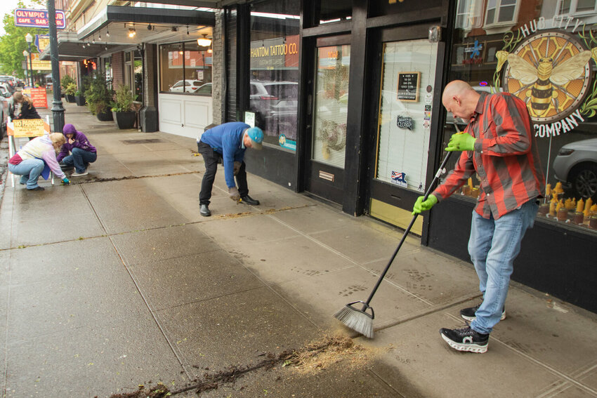 Volunteers Ron Sherrill, right, Don Haerling, center right, Catalina Cerny, center left, Sabrina Cerny, left, and Anastasia Cerny behind them work to clean the sidewalk along North Tower Avenue on Sunday, May 5, 2024, during the Centralia Downtown Association's volunteer Spring Cleanup event.