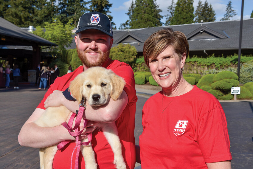 Northwest Battle Buddies volunteers Sheryl Burggraf, right, and her son, Andrew, show Bella, a golden retriever. The two are fostering the puppy before its training as a service dog for veterans.