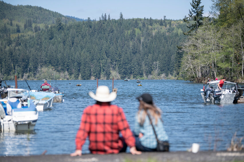 A couple sits on the edge of Mineral Lake during a fishing derby on Saturday, April 26.