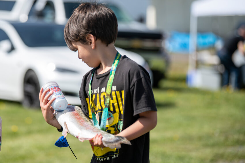Kameron Asakura carries a fish during a fishing derby at Mineral Lake on Saturday, April 26.