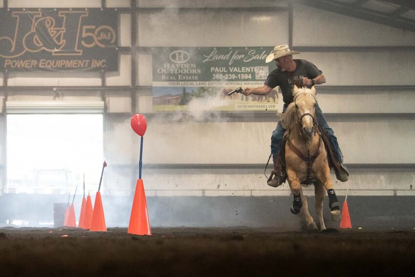 A competitor rides a horse through the arena while shooting balloon targets during the South Sound Mounted Shooters Spring Fling at the T90 Ranch in Tenino on Friday, May 9.