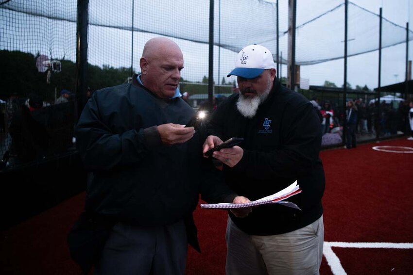 Officials take record of the scorebook after the 2B District 4 Championship Game was postponed due to darkness in Centralia on Thursday, May 15.