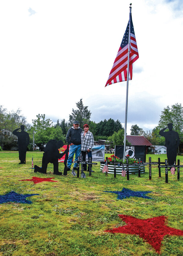 Battle Ground residents Cathy Foley and Brian Coulston stand with their veterans display that is up for Memorial Day through the Fourth of July at the intersection of Northeast 199th Street and Northeast 176th Avenue.