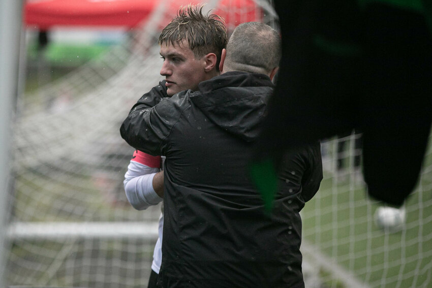 Tumwater senior Gavin Cuoio hugs an assistant coach after coming off the field against Archbishop Murphy in a Class 2A state opening round match on Tuesday, May 20 at Archbishop Murphy High School.
