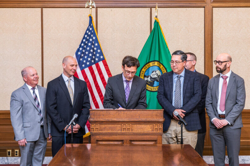 State Rep. Peter Abbarno, second from left, looks on as Washington Gov. Bob Ferguson signs his legislation on Monday, May 19, at the state Capitol in Olympia.