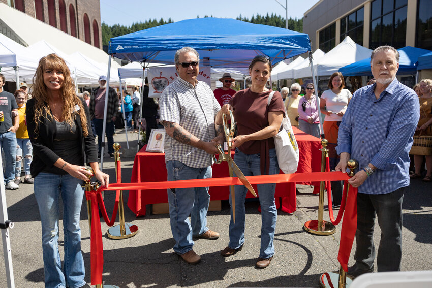 Mike and Heidi Peroni of Boistfort Valley Farm cut the ribbon for the 20th anniversary of the Chehalis Farmers Market in downtown Chehalis on Tuesday, June 3. At left is Centralia-Chehalis Chamber Ambassador Cara Legg and at right is Chehalis Mayor Tony Ketchum. The Centralia-Chehalis Chamber of Commerce hosted the ribbon-cutting ceremony. The Chehalis Farmers Market first opened in 2005. It&rsquo;s located along Boistfort and Market streets. The market operates every Tuesday from 11 a.m. to 4 p.m. from June to October. It features local farmers, artisans, food producers and crafters. In addition to its weekly Tuesday schedule, the market is now also open on the second Saturday of each month and will participate in Chehalis Fest on July 26. Learn more about the market at chehalisfarmersmarket.com.