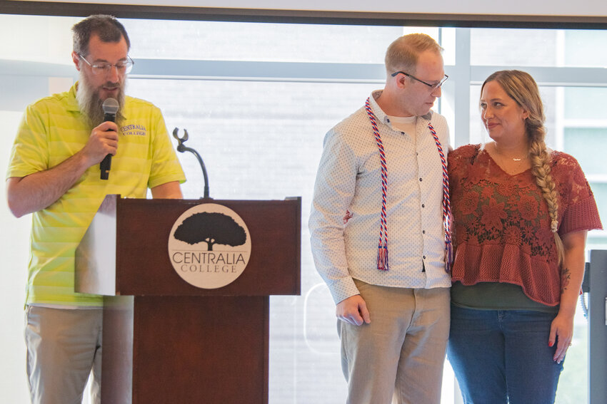 U.S. Marine Corps veteran Josh Pickett stands alongside his wife Ali Pickett after recieving his graduation cords from Centralia College Veterans Services coordinator Will Franklin inside the college's TransAlta Commons on Wednesday, June 11.