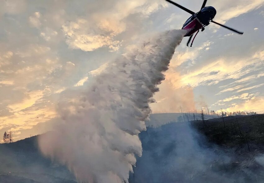 A helicopter dumps retardant on a fire.