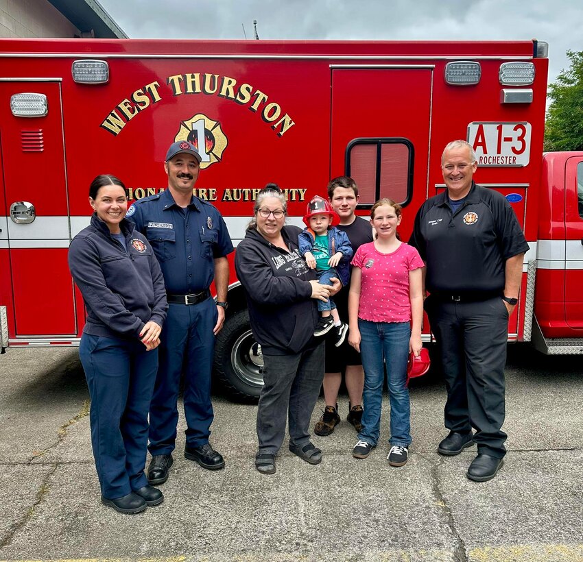 Amber Kirk, center, poses for a photo with three of her children and the West Thurston Fire team that cared for her when she suffered a heart attack and a 100%   blockage of one of her arteries on June 4.